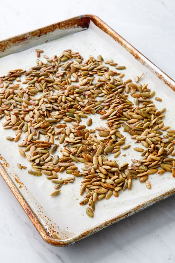 Parchment lined sheet pan with toasted pepitas, after baking when they are golden brown and crispy.