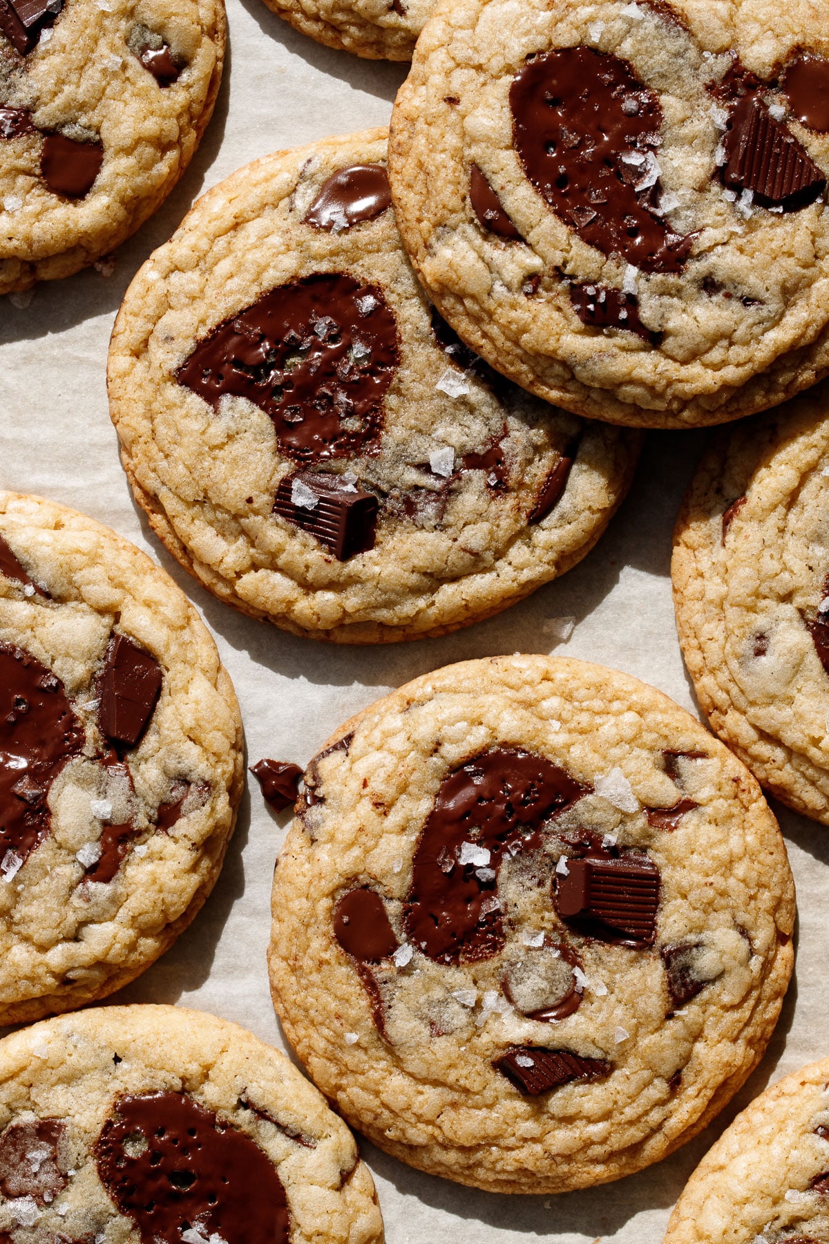 Overhead close up, Amaretto Chocolate Chip Cookies with melty puddles of dark chocolate and flakes of sea salt on top.