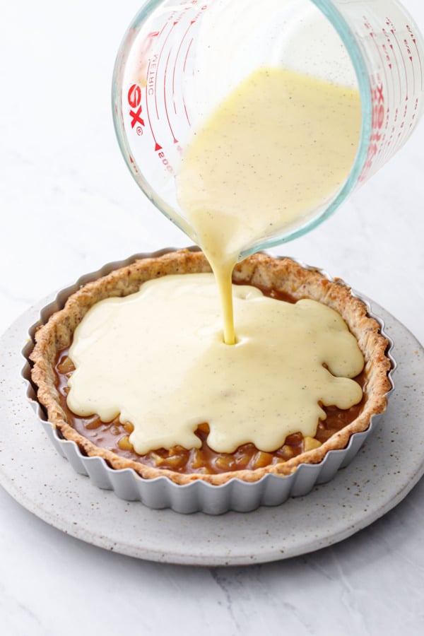 Pouring the vanilla almond crémeux on top of the set caramel apple layer in the tart shell.