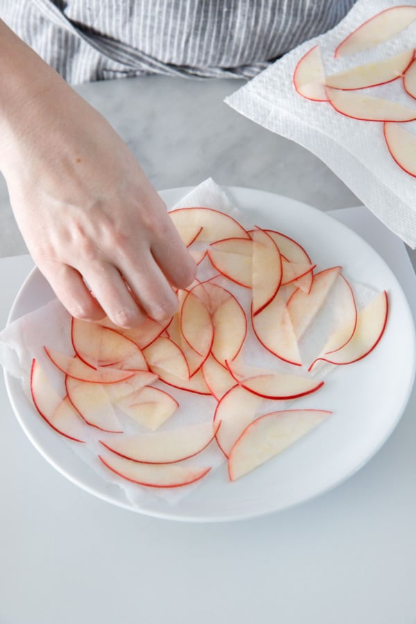 Arranging softened thin apple slices on a paper towel to dry.