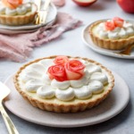 Caramel Apple Mousse Tart on a ceramic plate, with smaller tartlets and red apples in the background.