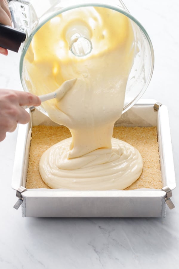 Pouring the freshly mixed cheesecake batter into the baking pan on top of the cookie crust.