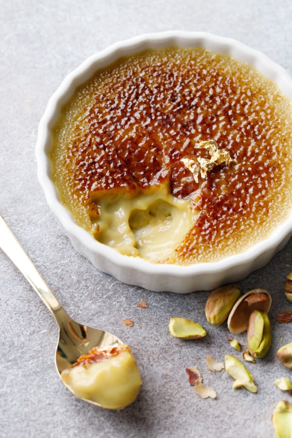 Closeup, spoonful of Pistachio Crème Brûlée, showing the creamy texture and soft green color of the custard underneath the caramelized sugar.