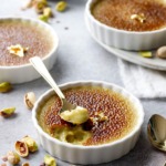 Spoonful out of a Pistachio Crème Brûlée, brown caramelized sugar on top and a light pistachio green color underneath.