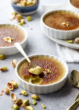 Spoonful out of a Pistachio Crème Brûlée, brown caramelized sugar on top and a light pistachio green color underneath.