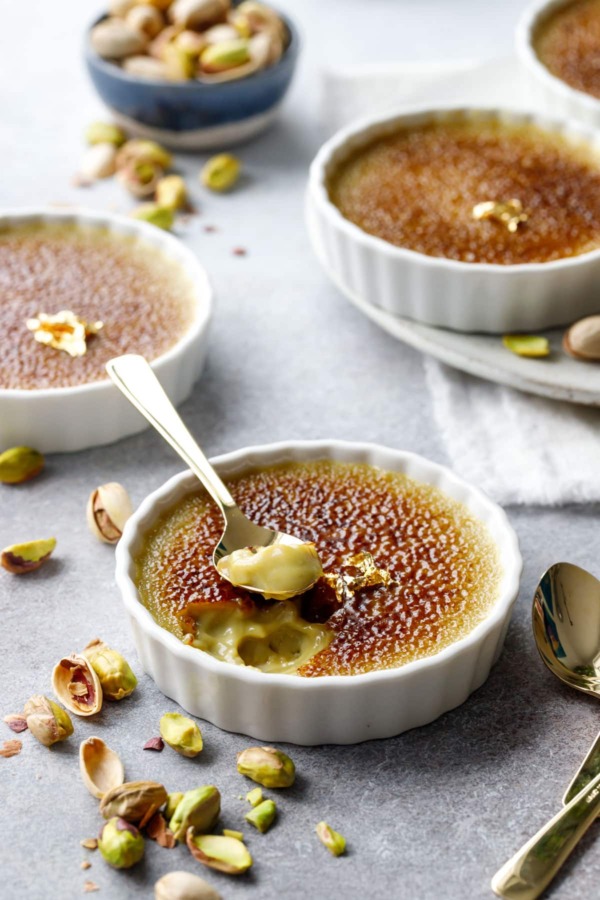 Spoonful out of a Pistachio Crème Brûlée, brown caramelized sugar on top and a light pistachio green color underneath.