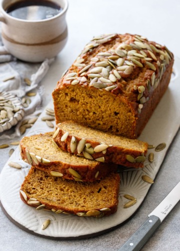 Spiced Pumpkin Banana Bread with three slices laying down, cup of coffee in the background.