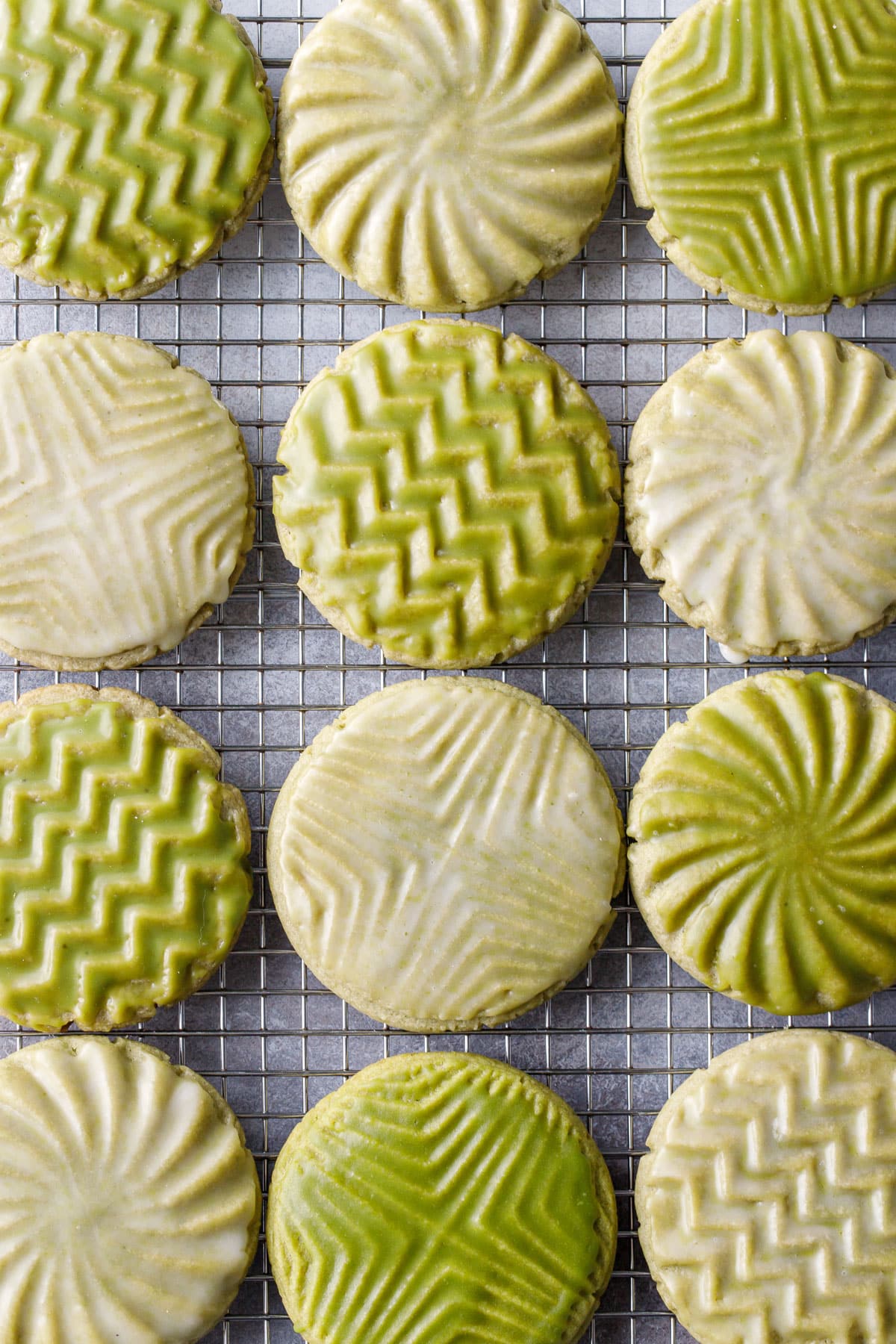 Overhead, wire rack with neat rows of Glazed Matcha Sugar Cookies with alternating white and green glazes and geometric designs.