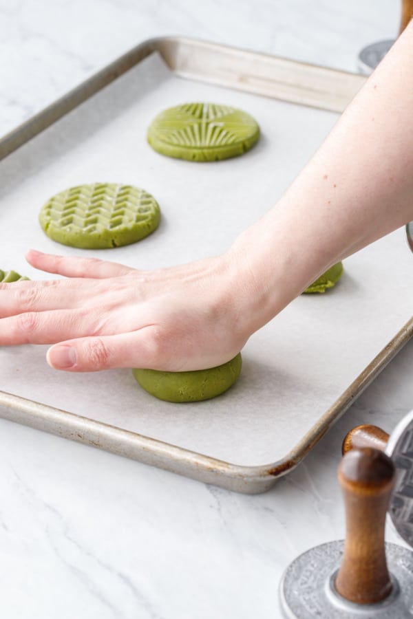 Pressing the dough ball into a flat disk before stamping.