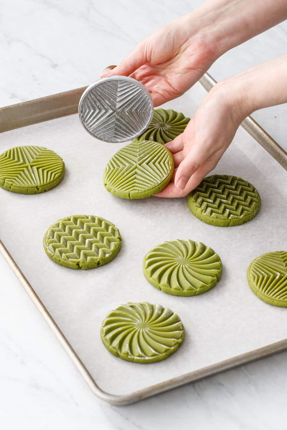 Arranging the stamped cookies on a parchment-lined baking sheet with a few inches of space between them.