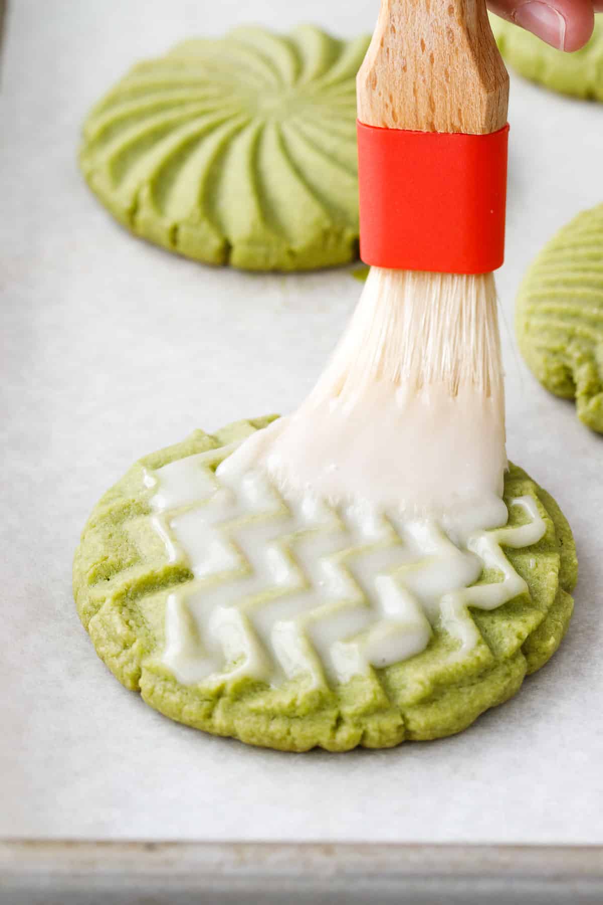 Closeup of brushing the warm baked cookies with a thin white sugar glaze.