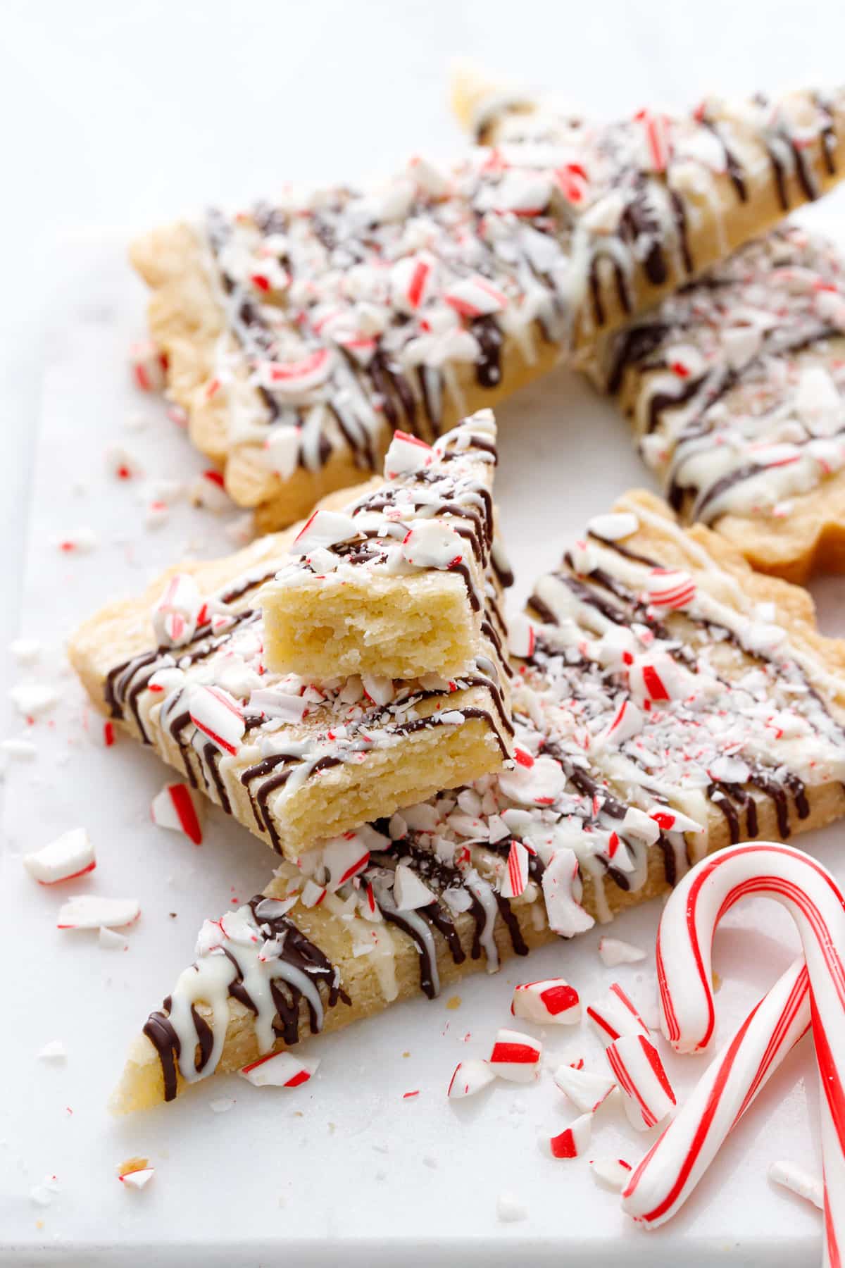 Messy arrangment of Peppermint Bark Shortbread, one cookie broken in two to show the tender interior texture.