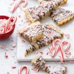 Peppermint Bark Shortbread on marble, with messy bits of candy canes and a red bowl of crushed candy canes on the side.