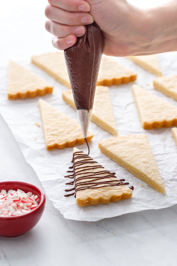 Drizzling the wedges of shortbread with dark chocolate.