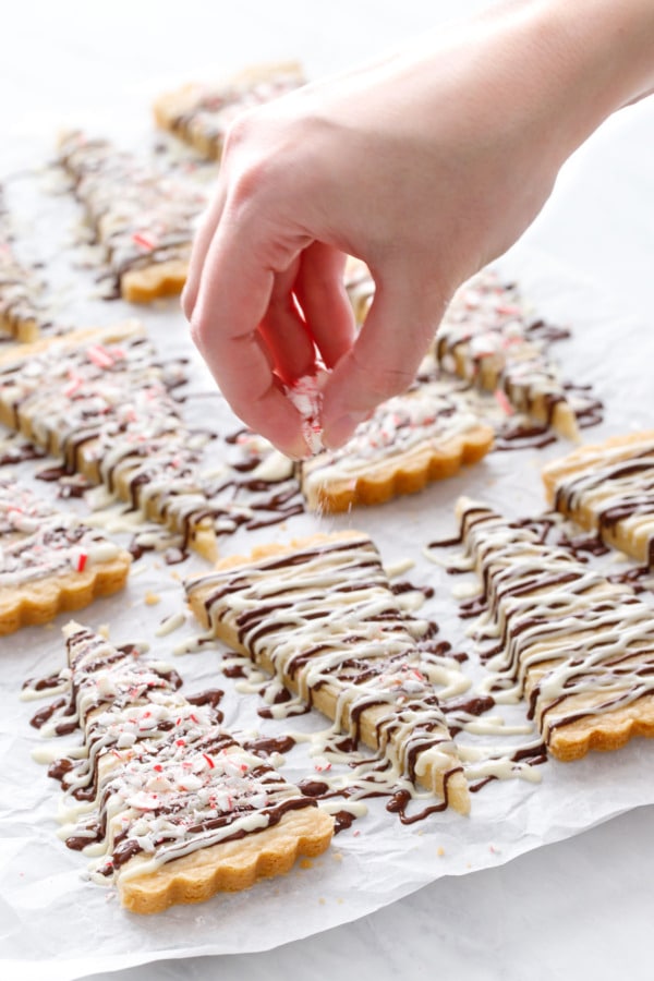 Sprinkling crushed candy canes on top of the freshly drizzled chocolate.