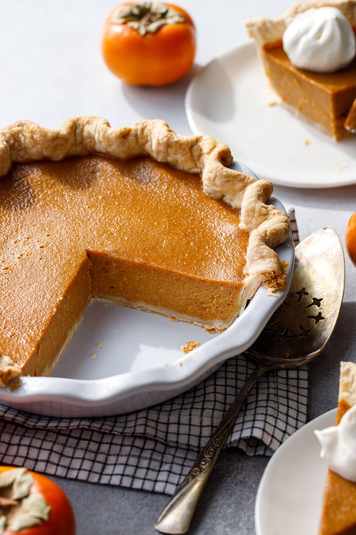 Persimmon Pie in a white ceramic pie plate, with a wedge cut out to show the interior texture of the pie.