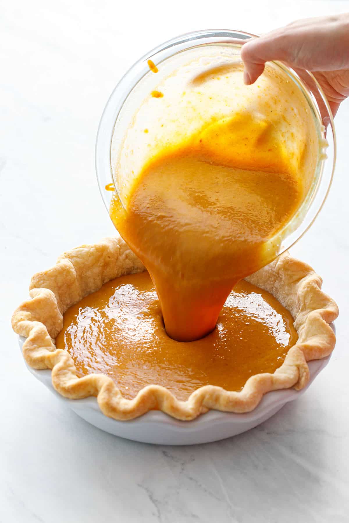 Pouring the Persimmon Pie filling into a par-baked pie crust.