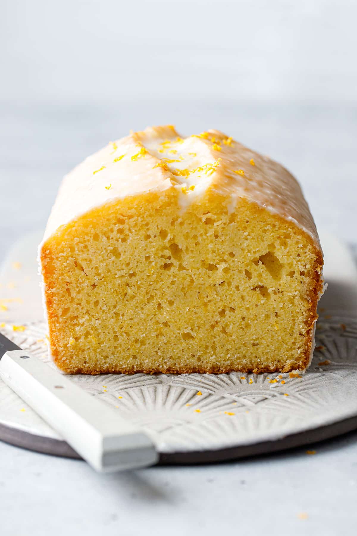 Cross section cut Meyer Lemon Olive Oil Loaf Cake, showing the texture of the interior crumb and thin layer of glaze on the outside.