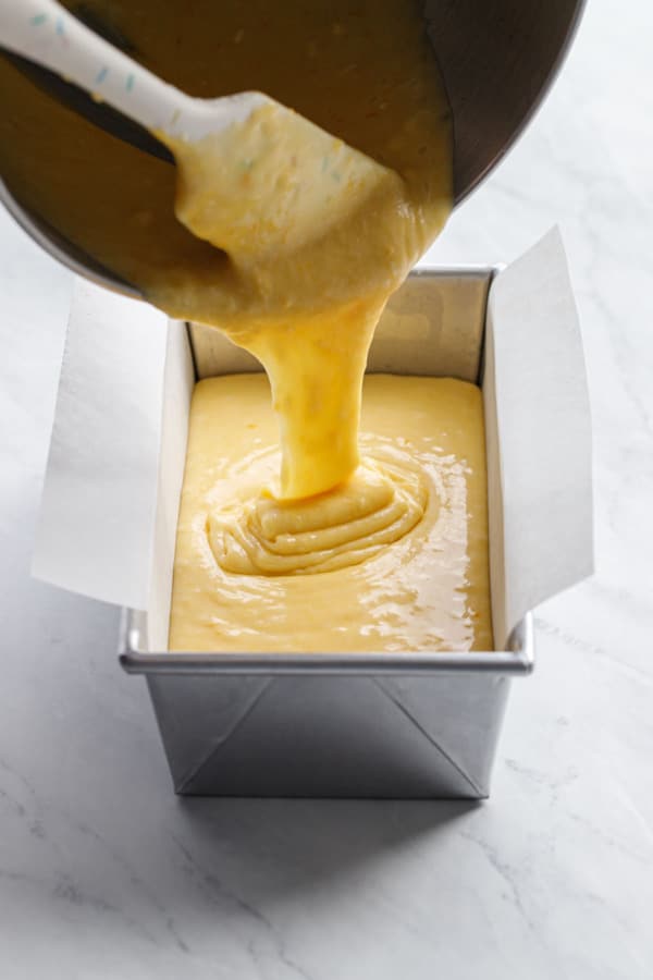 Pouring the Meyer Lemon Olive Oil batter into a parchment-lined loaf pan.