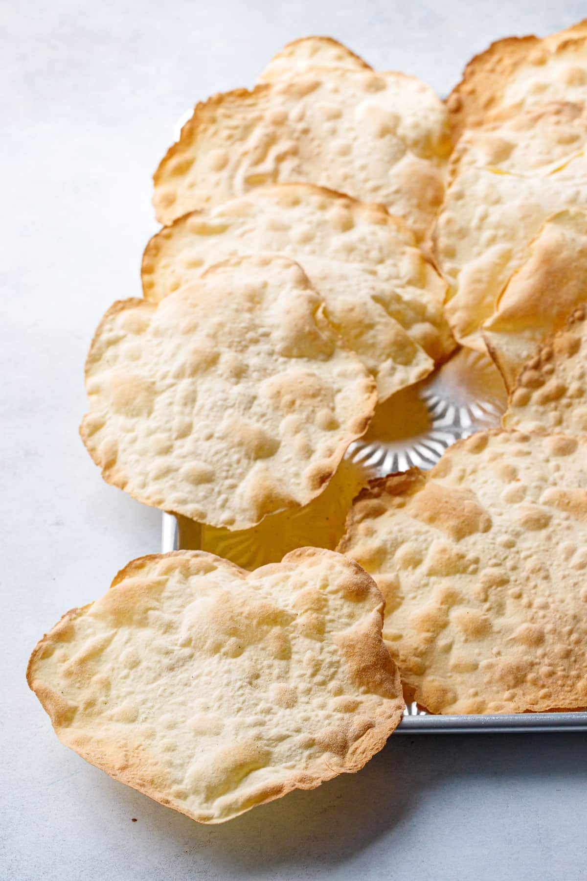 Pan of freshly baked sourdough semolina crackers, fresh out of the oven, showing the bubbly surface and golden brown edges.