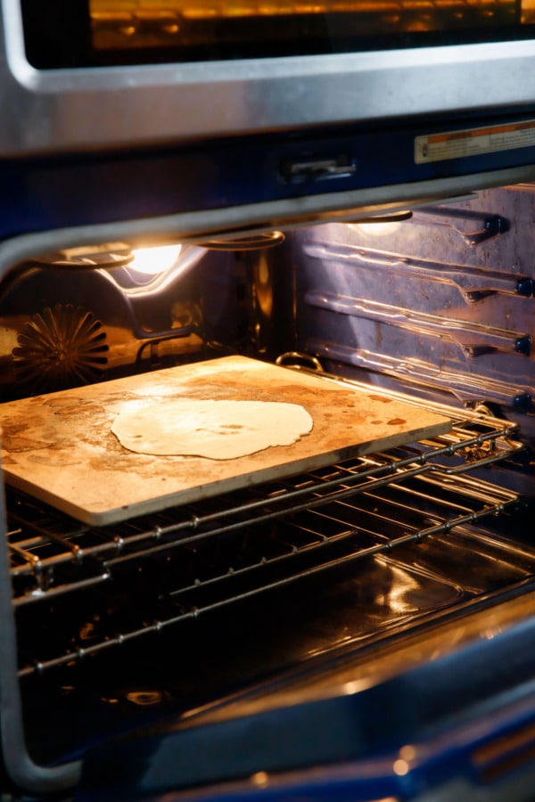 Cracker dough on a pizza stone in a hot oven before baking.