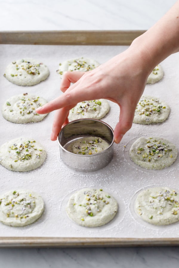 Swirling the pistachio dacquoise rounds with a cookie cutter to make them the correct size and shape.