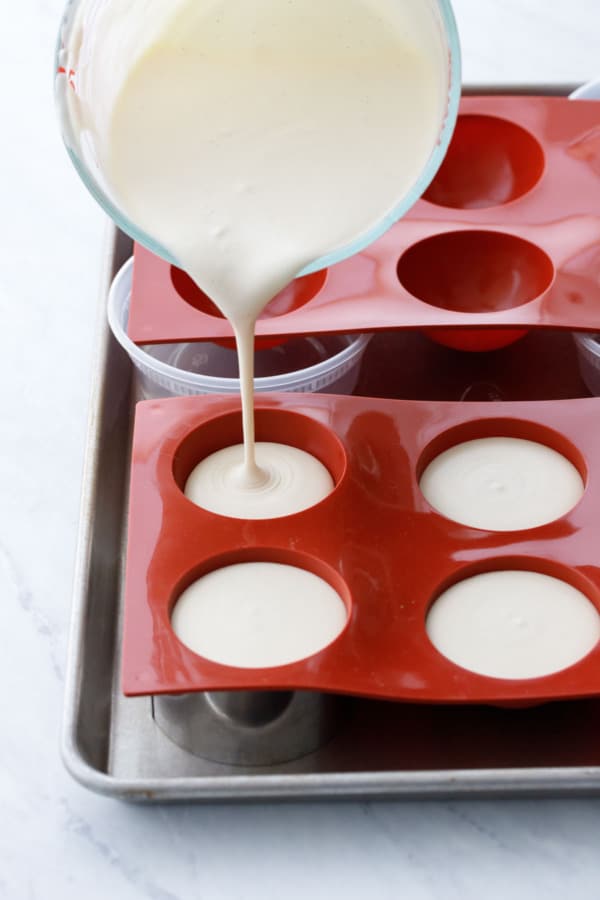 Pouring the lemon mousse into silicone dome molds.