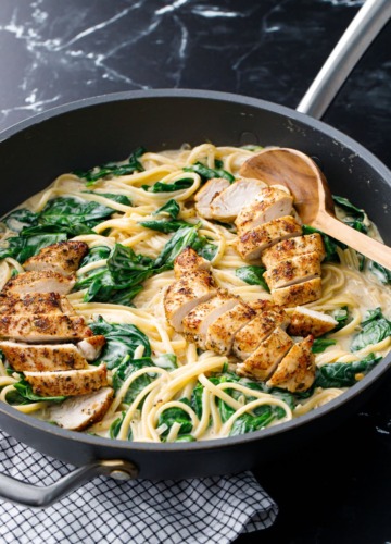Large nonstick skillet with Creamy Chicken Florentine Pasta and wooden spoon.