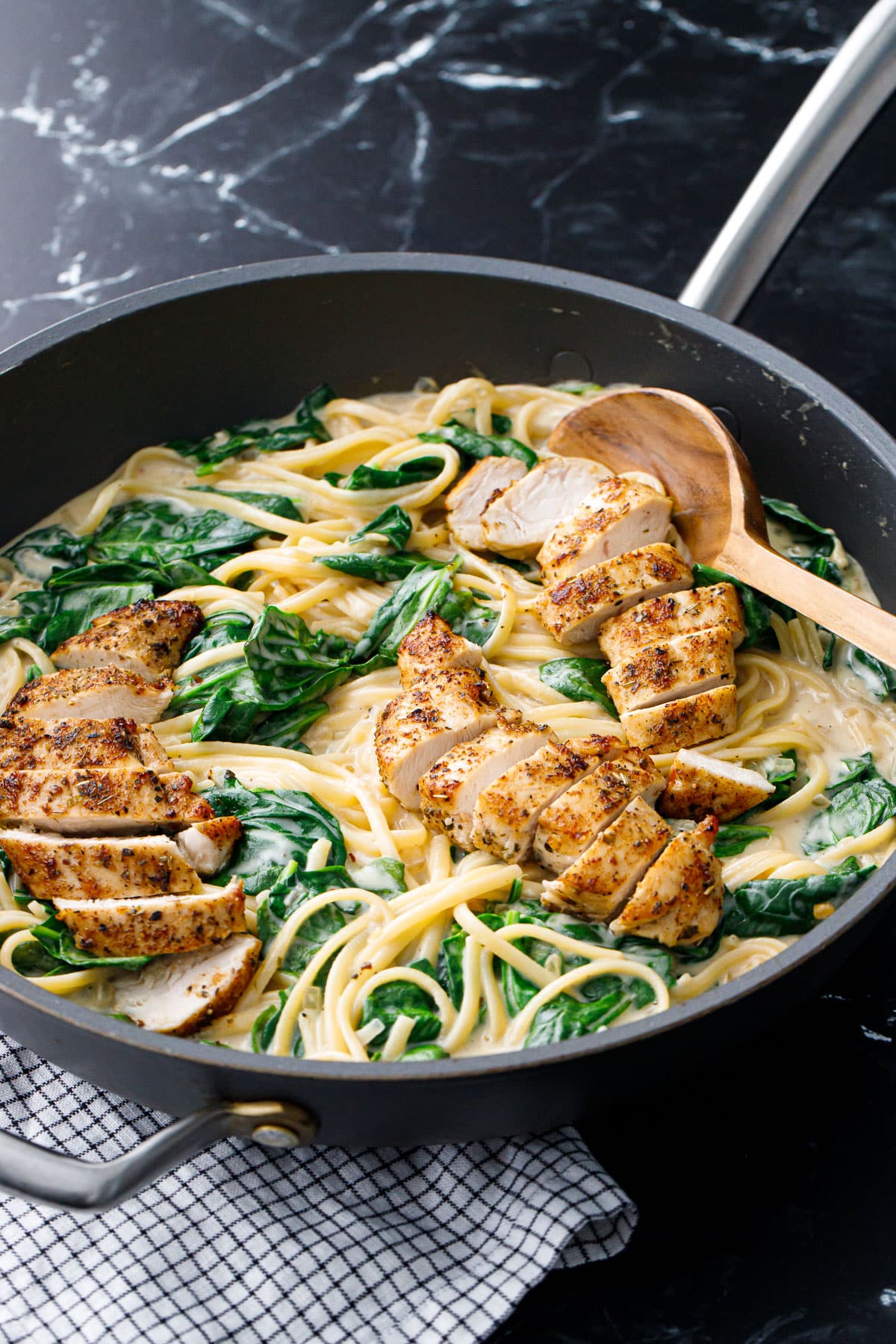 Large nonstick skillet with Creamy Chicken Florentine Pasta and wooden spoon.