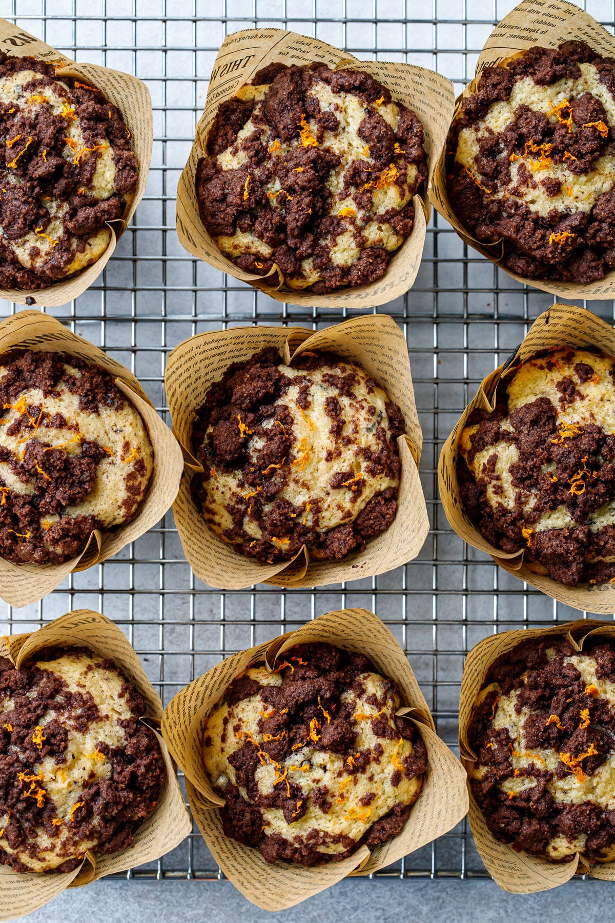 Overhead, nine Chocolate Orange Streusel Muffins on a wire baking rack, showing the texture of the chocolate streusel baked on top.