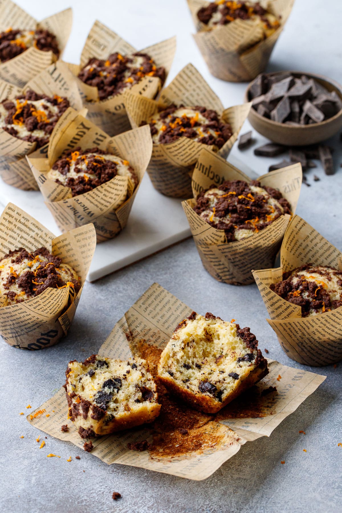 Chocolate Orange Streusel Muffins on a gray background, one muffin broken in half to show the fluffy interior texture.