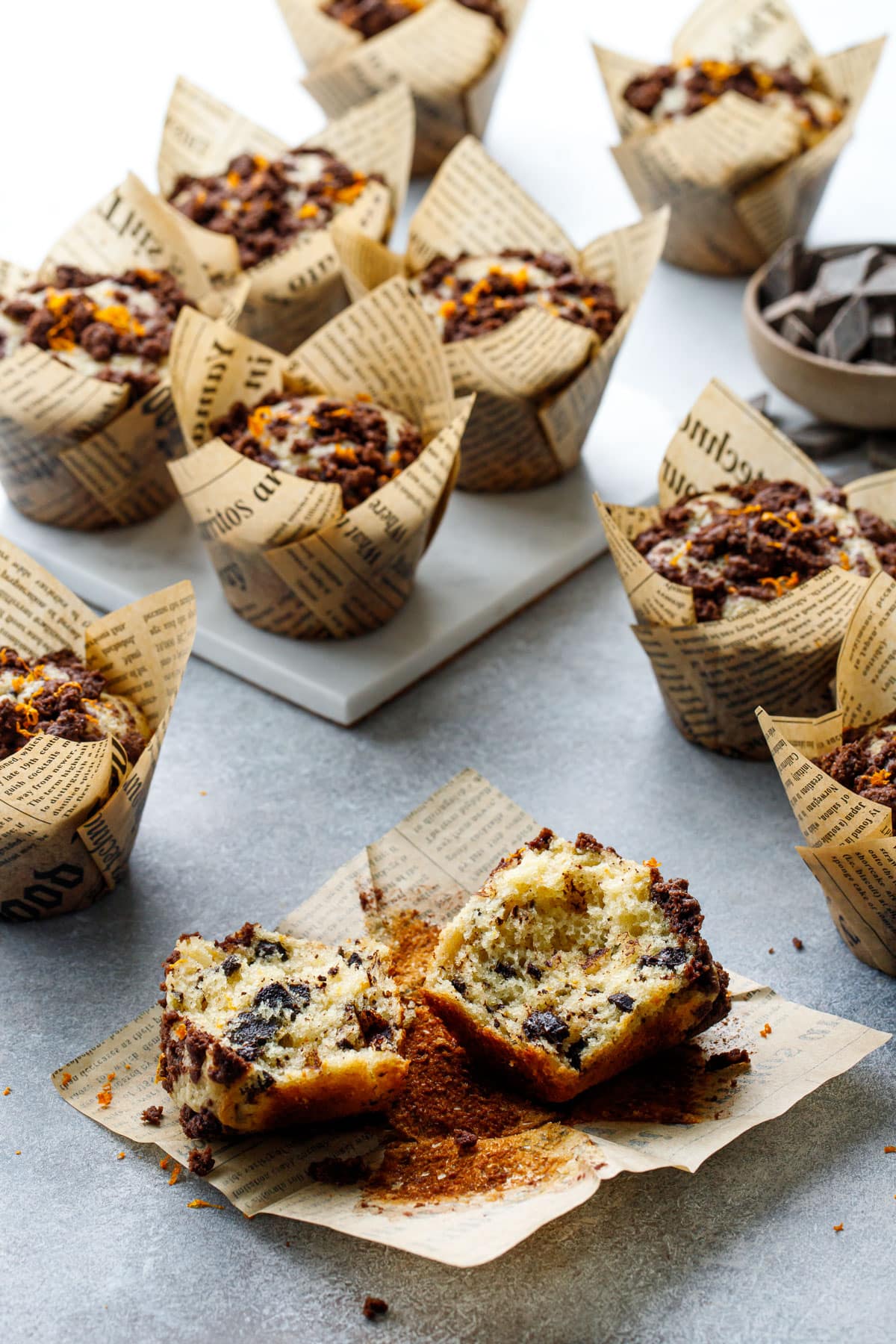 Chocolate Orange Streusel Muffins on a gray background, one muffin broken in half to show the fluffy interior texture.