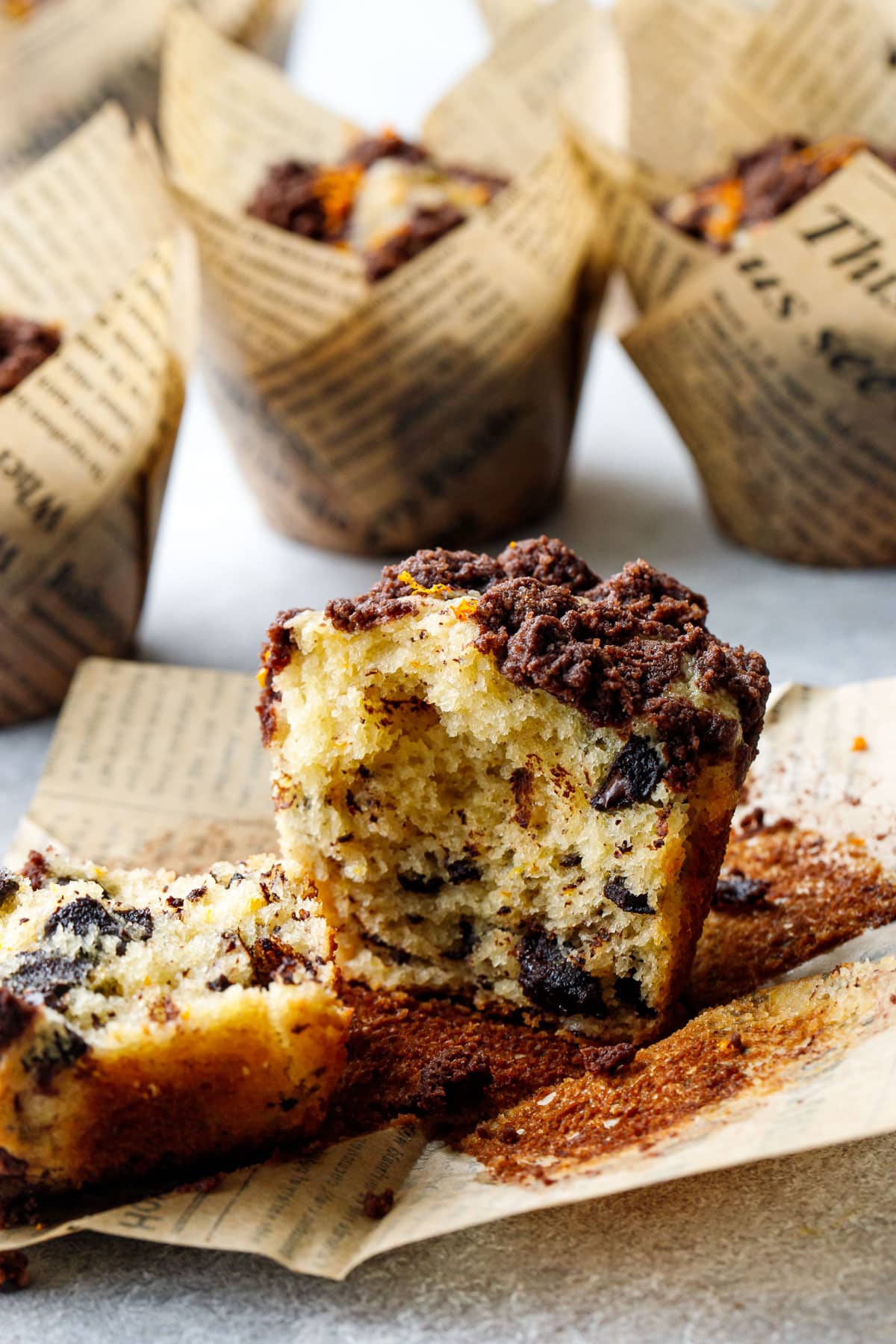 Chocolate Orange Streusel Muffin broken in half to show the interior texture, sitting on the peeled off paper wrapper.