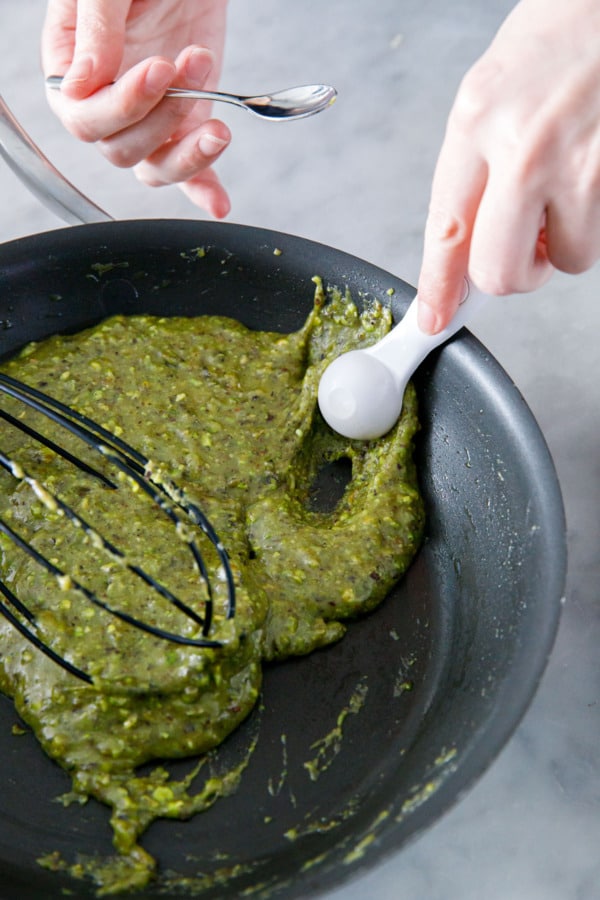 Scooping teaspoonfuls of batter for each cookie.