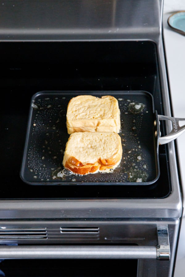 Stuffed French toasts on a nonstick skillet on the stove, before flipping.