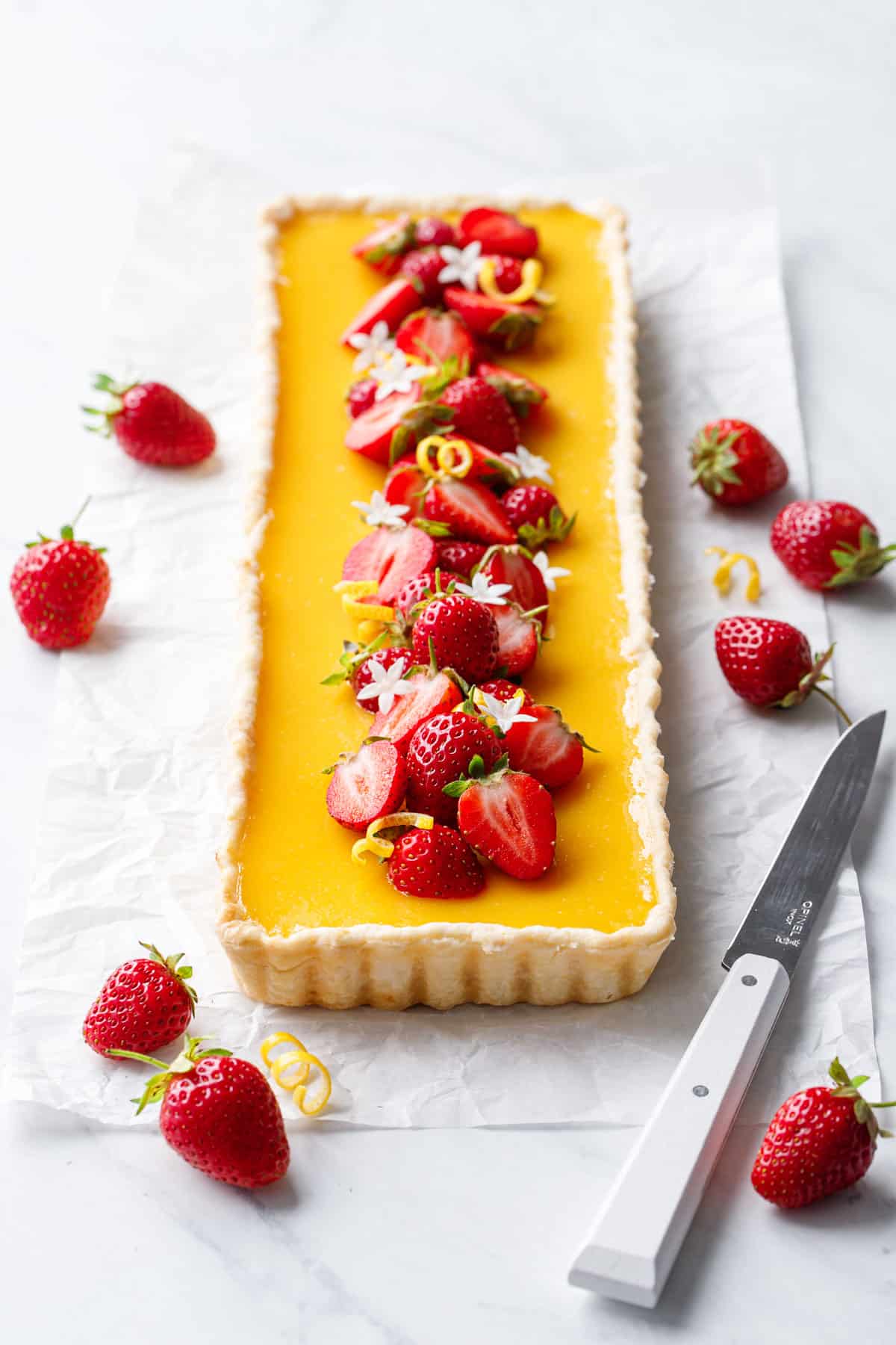 Rectangular Strawberry Meyer Lemon Tart topped with fresh strawberries, lemon twists and edible flowers.