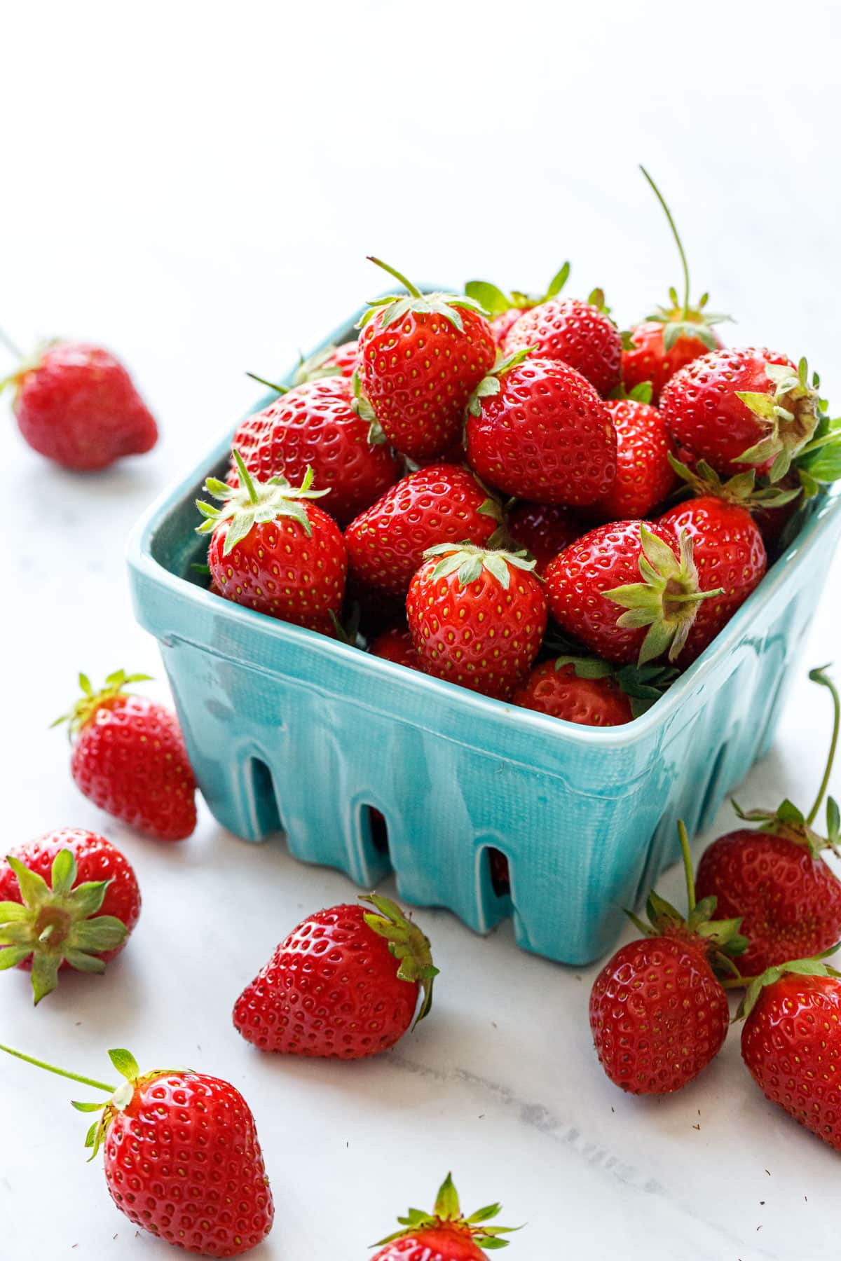 Fresh picked strawberries in a turquoise ceramic berry basket.