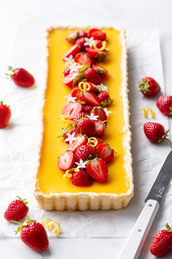 Rectangular Strawberry Meyer Lemon Tart topped with fresh strawberries, lemon twists and edible flowers.