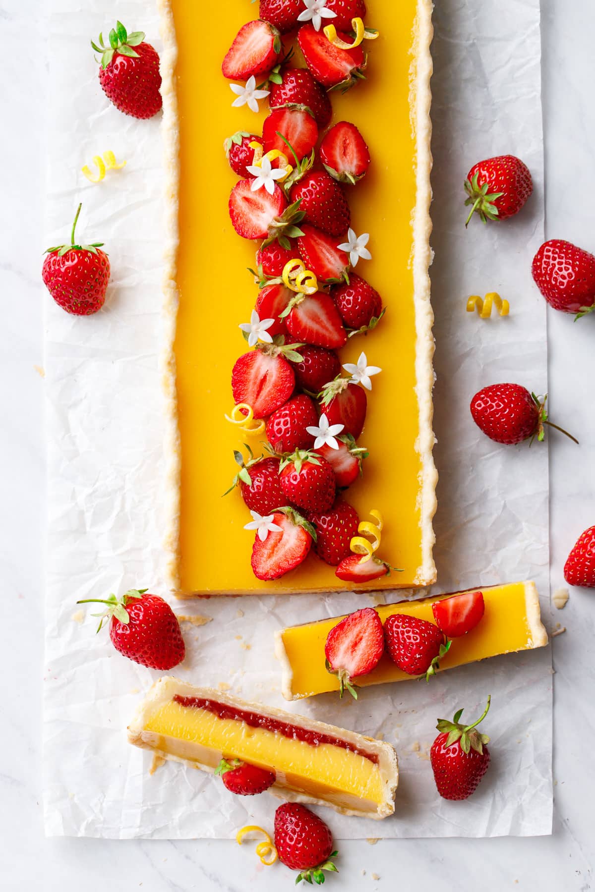 Overhead, rectangular Strawberry Meyer Lemon Tart with slices cut to show the cross section of layers.