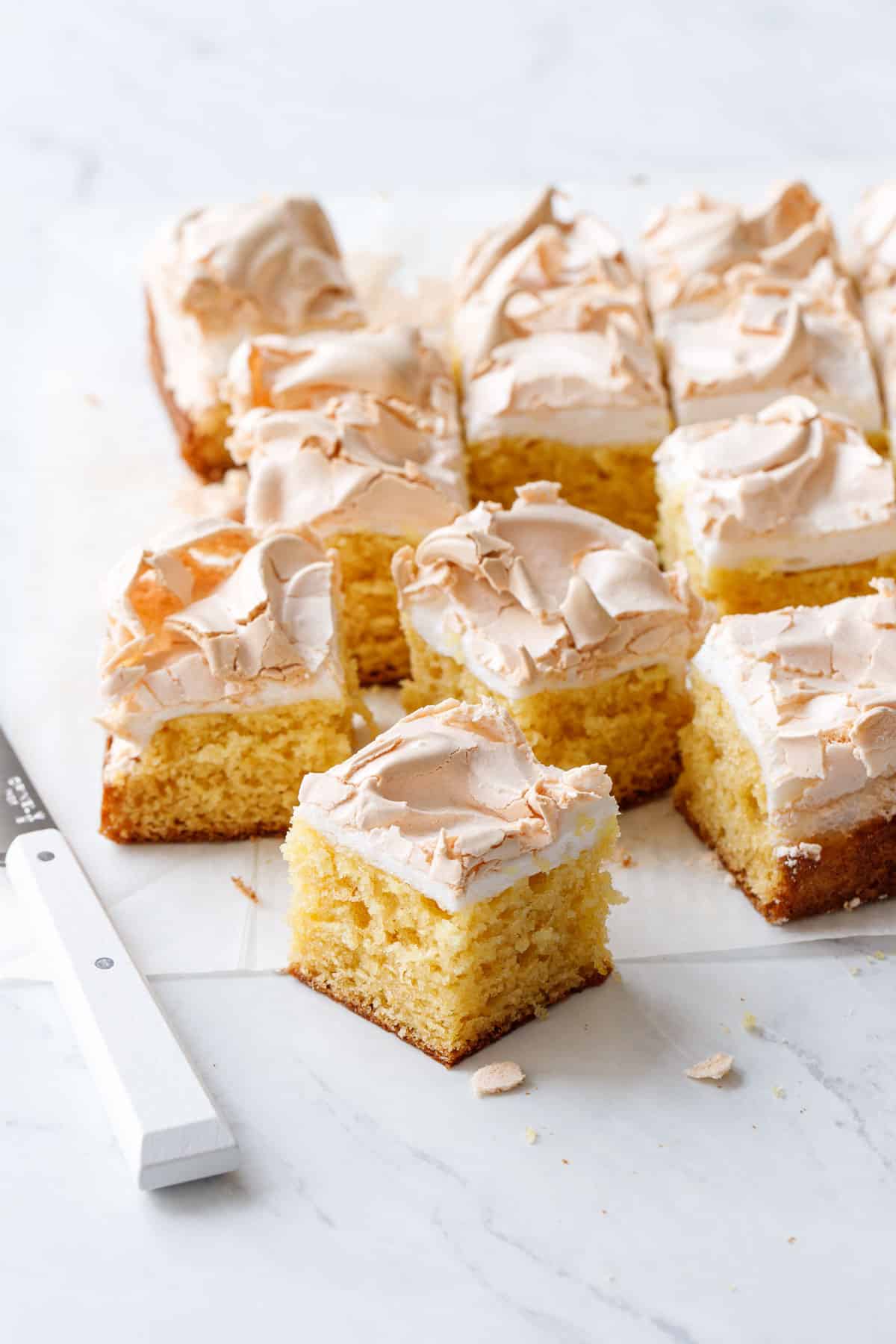 Lemon Meringue Butter Cake cut into squares showing the layers of tender yellow butter cake and toasted meringue swirled on top.