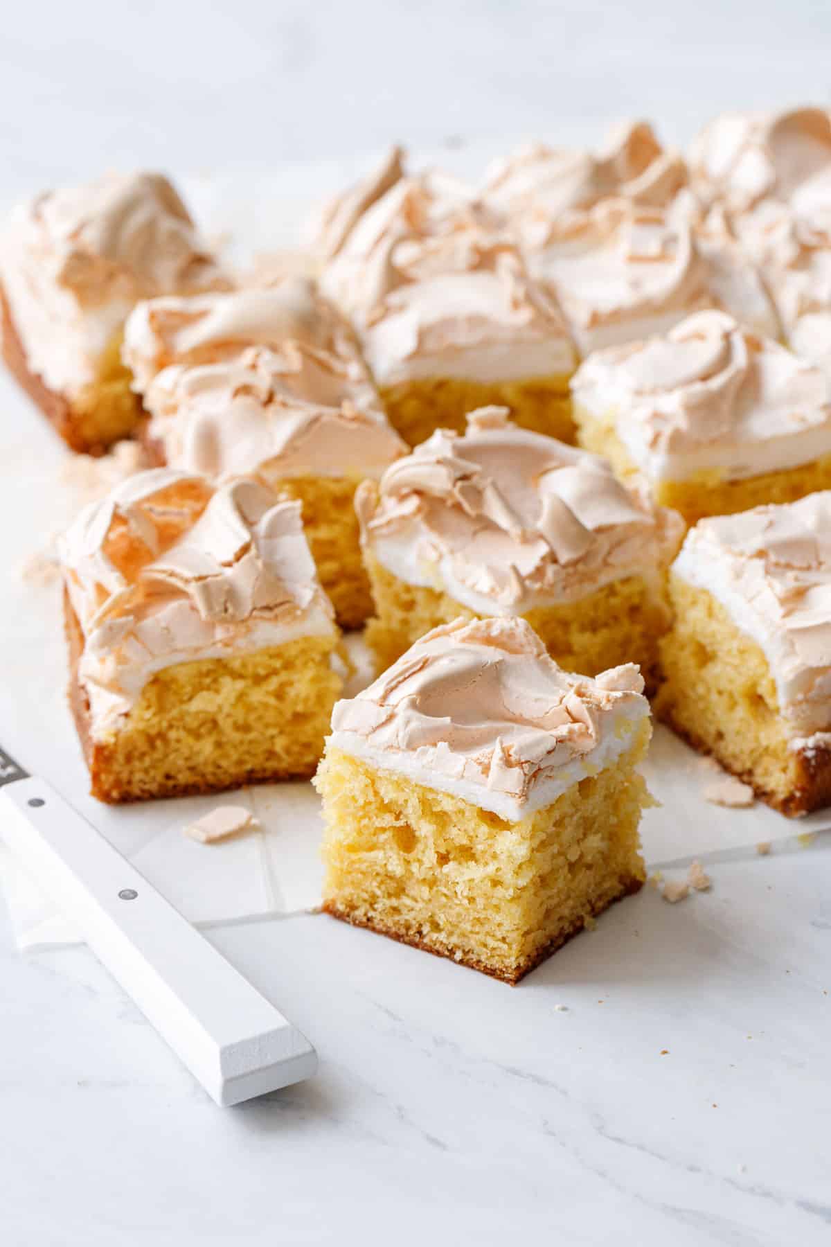 Squares of Lemon Meringue Butter Cake with a coarsely textured, yellow colored crumb and a light golden toasted meringue topping.
