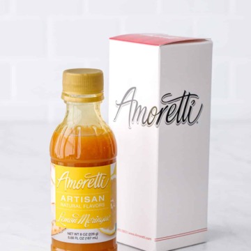 Bottle of Amoretti Lemon Meringue Artisan Flavoring with Amoretti box packaging on a white marble background.