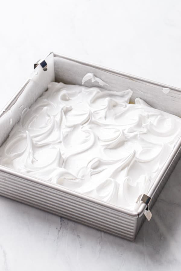Swirls of bright white, glossy meringue on top of the cake before baking.
