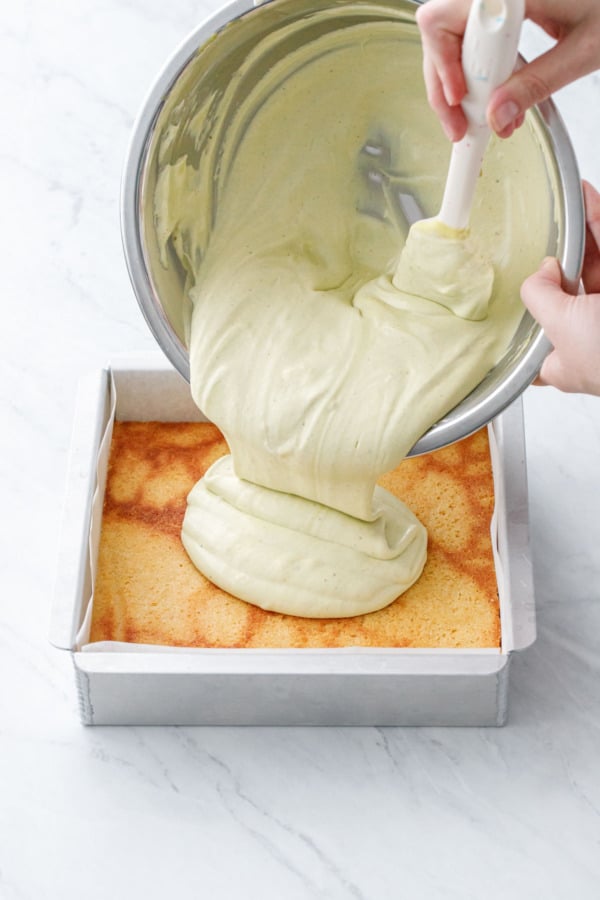 Pour pistachio cream mixture into the parchment-lined baking pan on top of the first blondie layer.