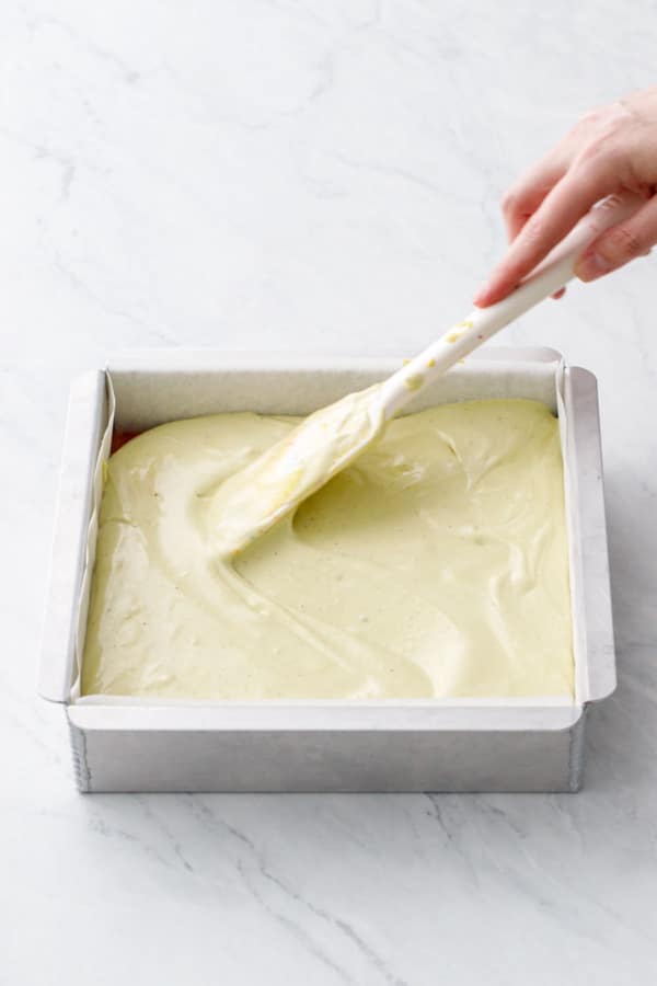 Spreading no-churn pistachio ice cream into an even layer in the baking pan.