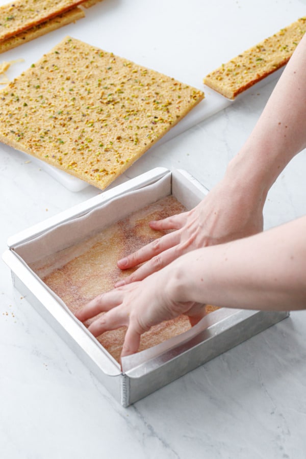 Pressing the bottom blondie layer into the bottom of an 8-by-8-inch baking pan.