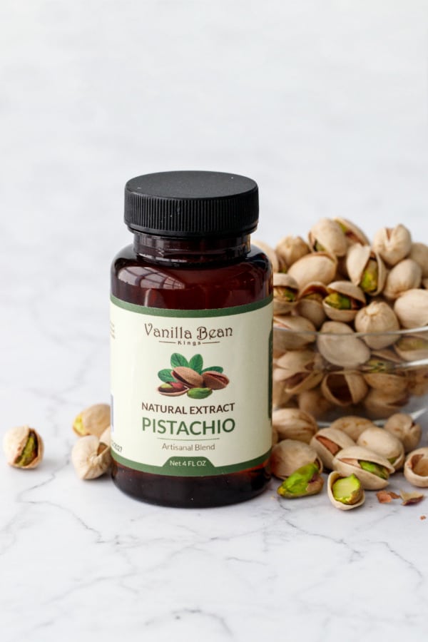 Vanilla Bean Kings Pistachio Extract bottle with bowl of pistachios.