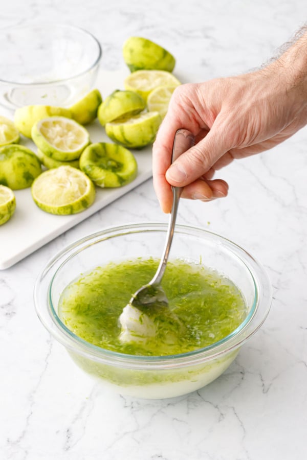 Stirring lime cordial mixture with a spoon until the sugar is mostly dissolved.