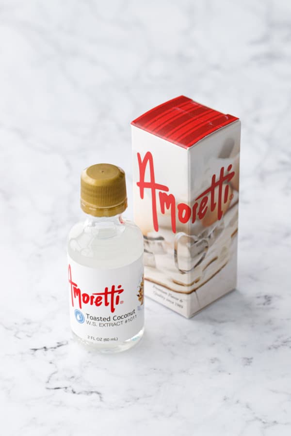 Bottle of Amoretti Toasted Coconut Extract with box packaging on a marble background.