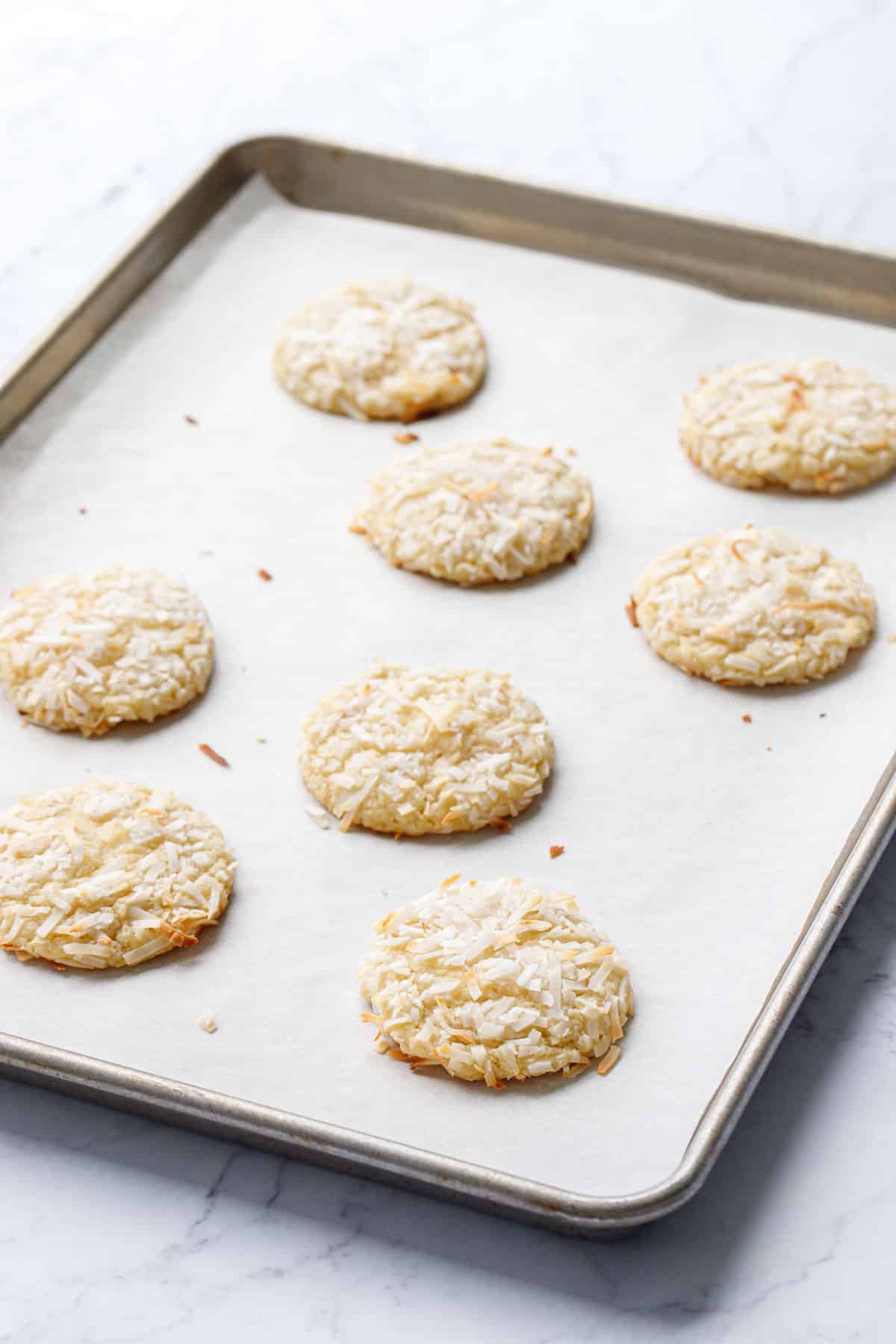 Toasted Coconut Sugar Cookies on a baking pan lined with parchment, immediately after baking.